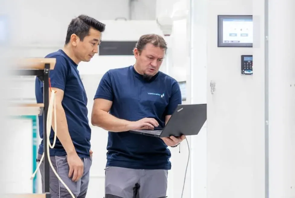 Two Vendanor technicians performing final inspection of a propane machine using a laptop in the workshop.