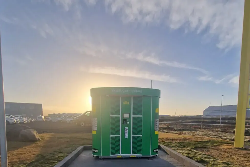 Green Olis-branded Vendanor Propane Vending Machine standing outdoors at sunset.