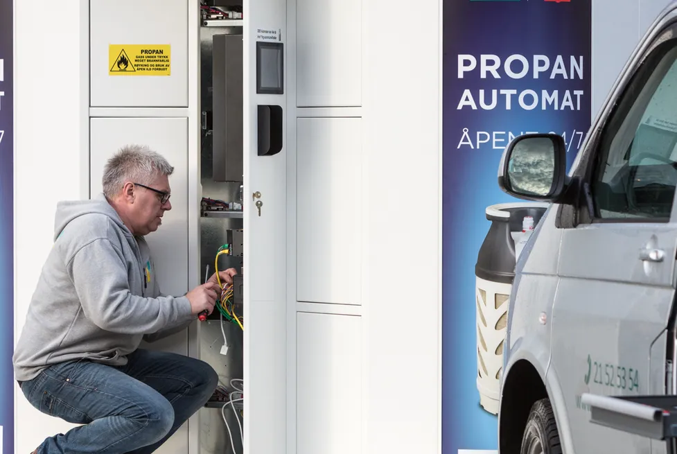 Technician servicing a Vendanor Propane Vending Machine marked Propanautomat 24/7 at a Shell and 7-Eleven station.
