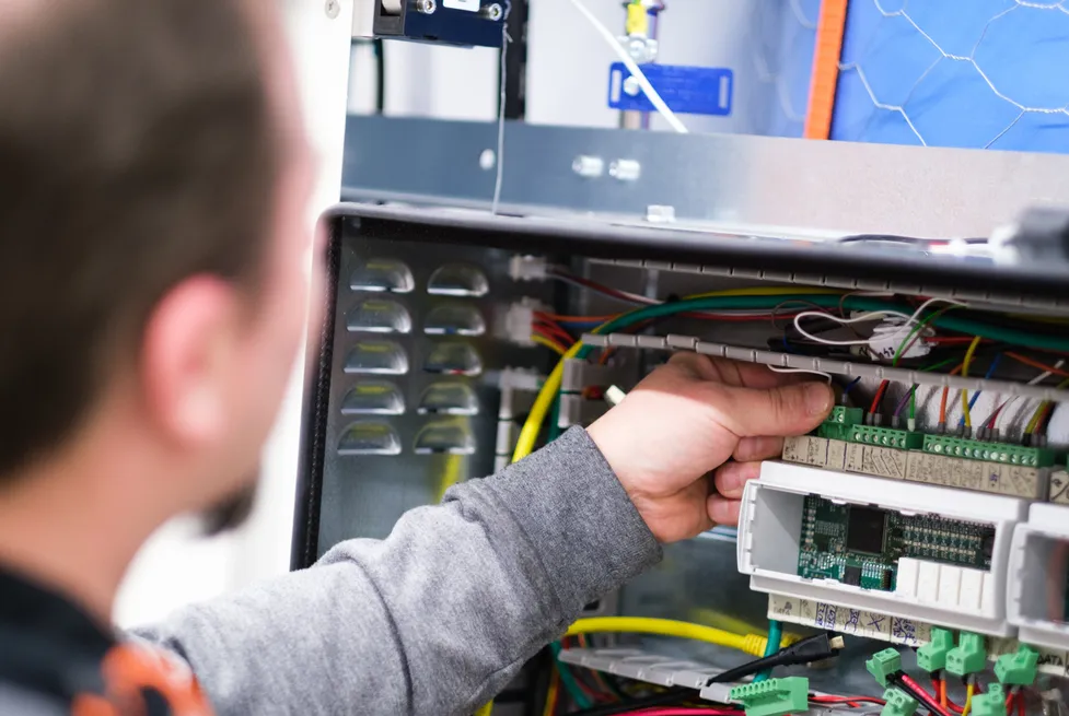 A Vendanor technician working on the electronics and wiring inside a vending machine during production.