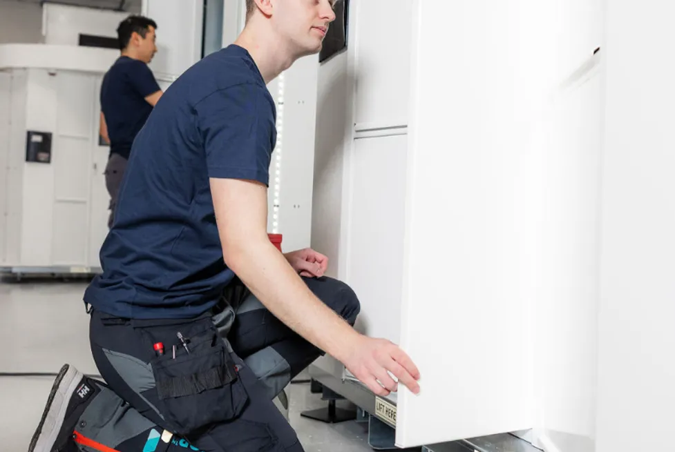 Two Vendanor technicians assemble white machine cabinets on the production floor.